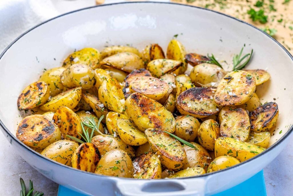 skillet with crispy potatoes and fresh herbs