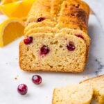 gluten free orange cranberry loaf cut into slices with fresh fruit